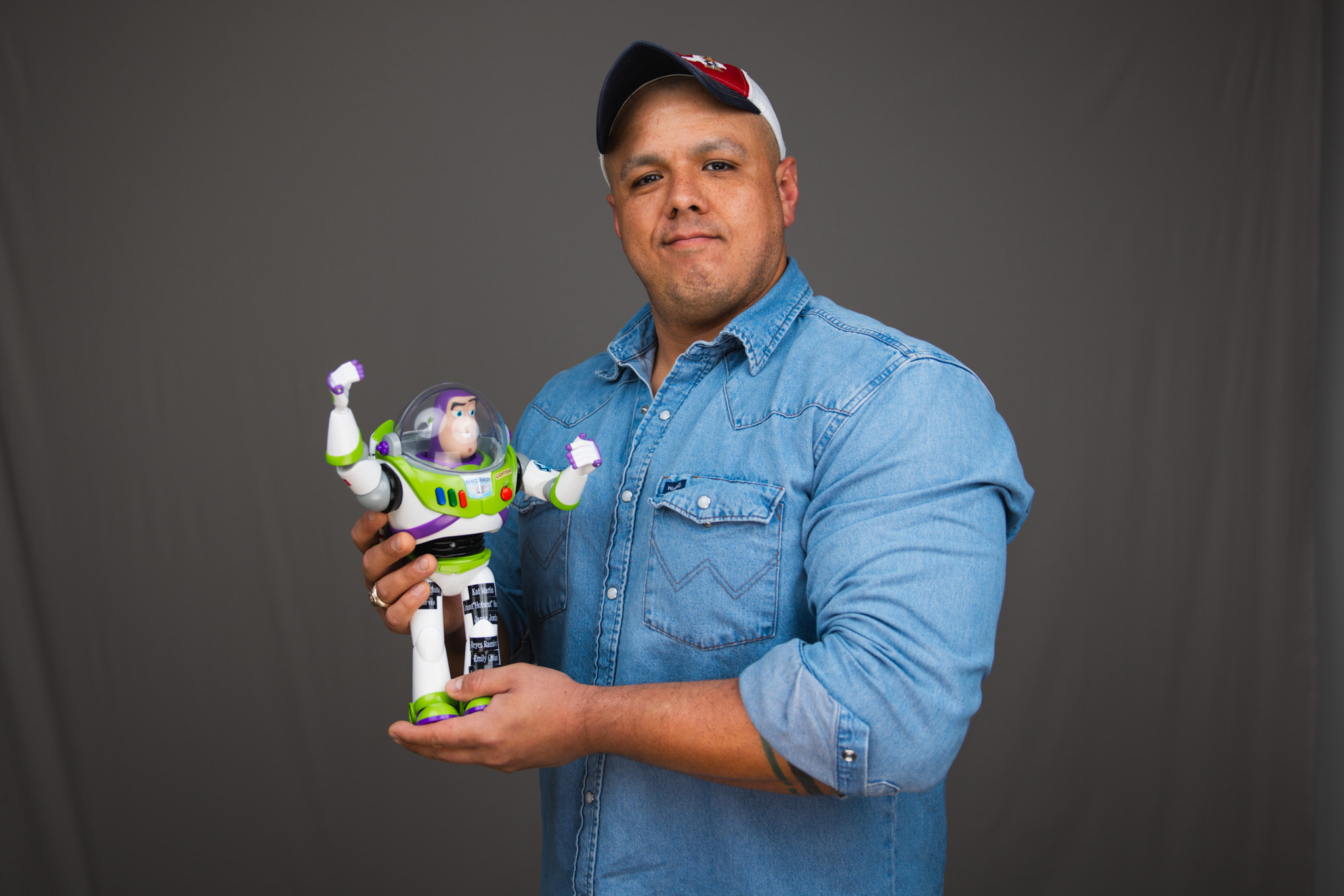 Video Communications Coordinator Chris Jarvis holding Buzz Lightyear figure against a gray backdrop