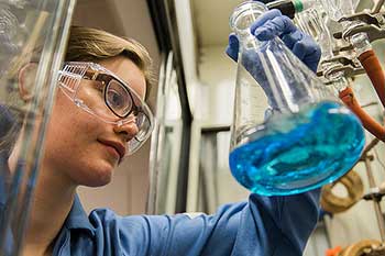 student holding a beaker filled with blue liquid