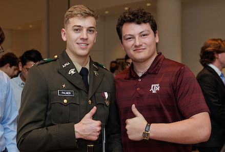 Two students with a gigem thumbs up. 