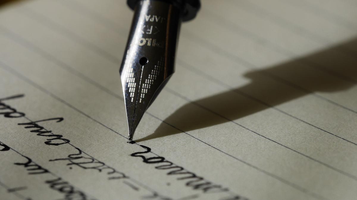 A close-up photograph of a fountain pen with writing in cursive