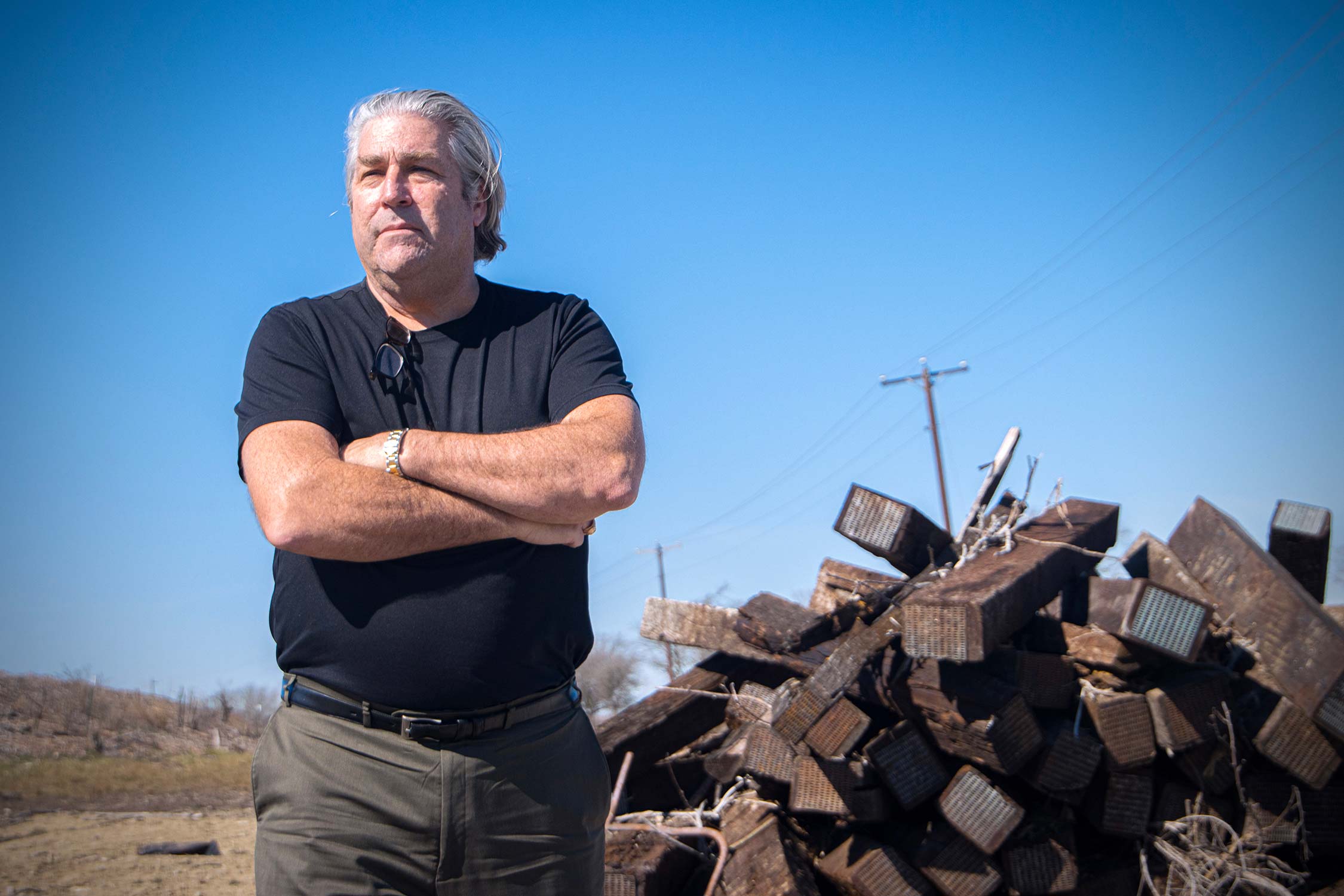 1990 Texas A&M University chemistry Ph.D. graduate Carl McAfee, standing in front of a pile of discarded wooden railroad ties