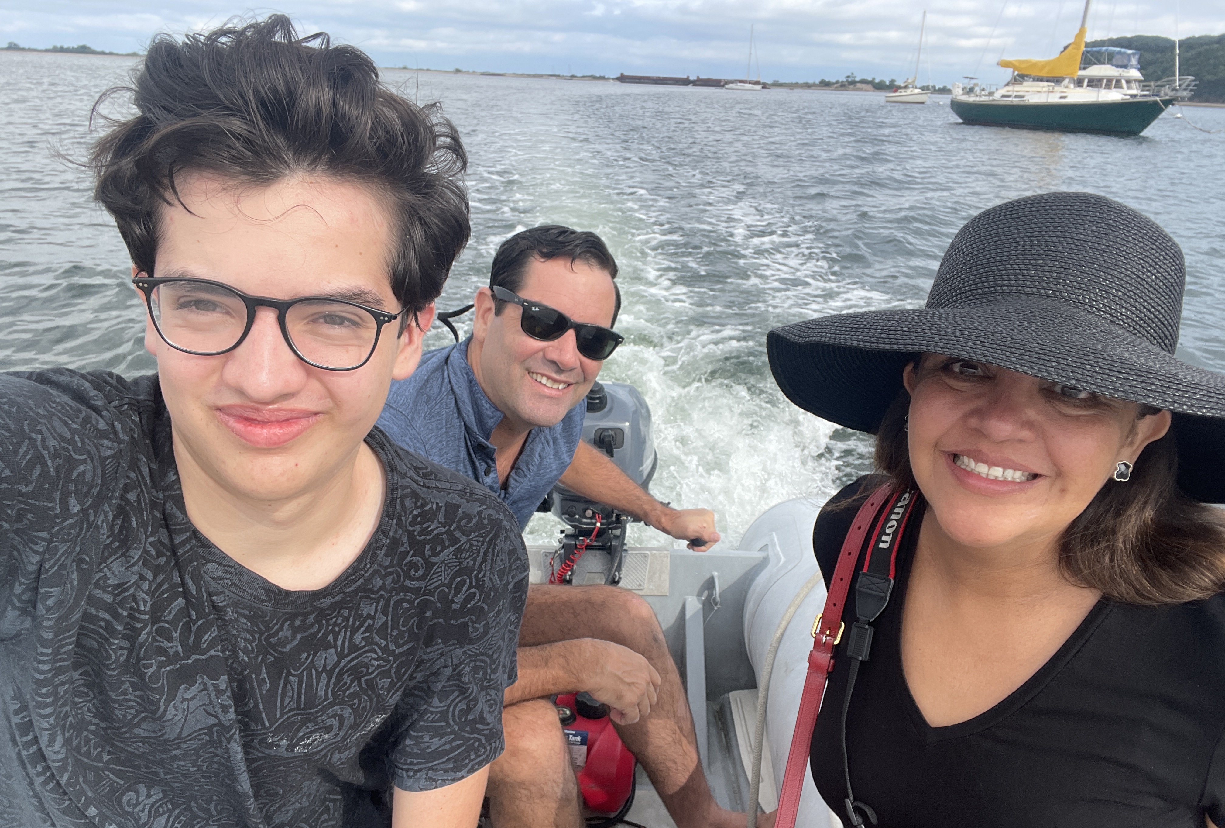 Texas A&M former student Brett Graham steers the outboard motor of a boat, accompanied by his wife and son.