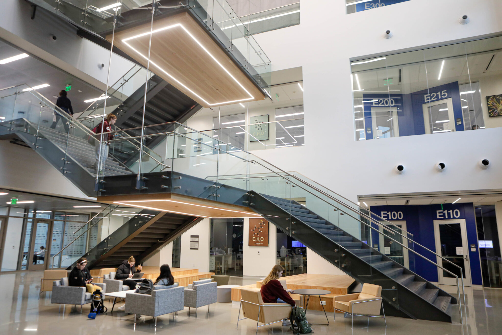 Interior view of the Instructional Laboratory and Innovative Learning Building at Texas A&M University featuring students seated in the foyer, a two-way staircase, and partial views of the building’s first two floors