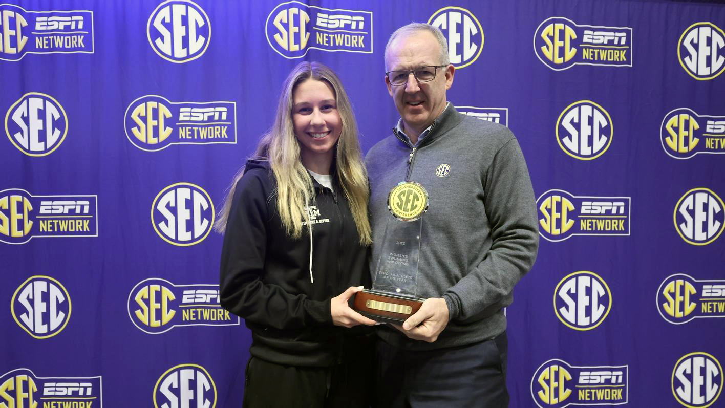 Texas A&M swimmer Chloe Stepanek receives a trophy and congratulations from Southeastern Conference Commissioner Greg Sankey