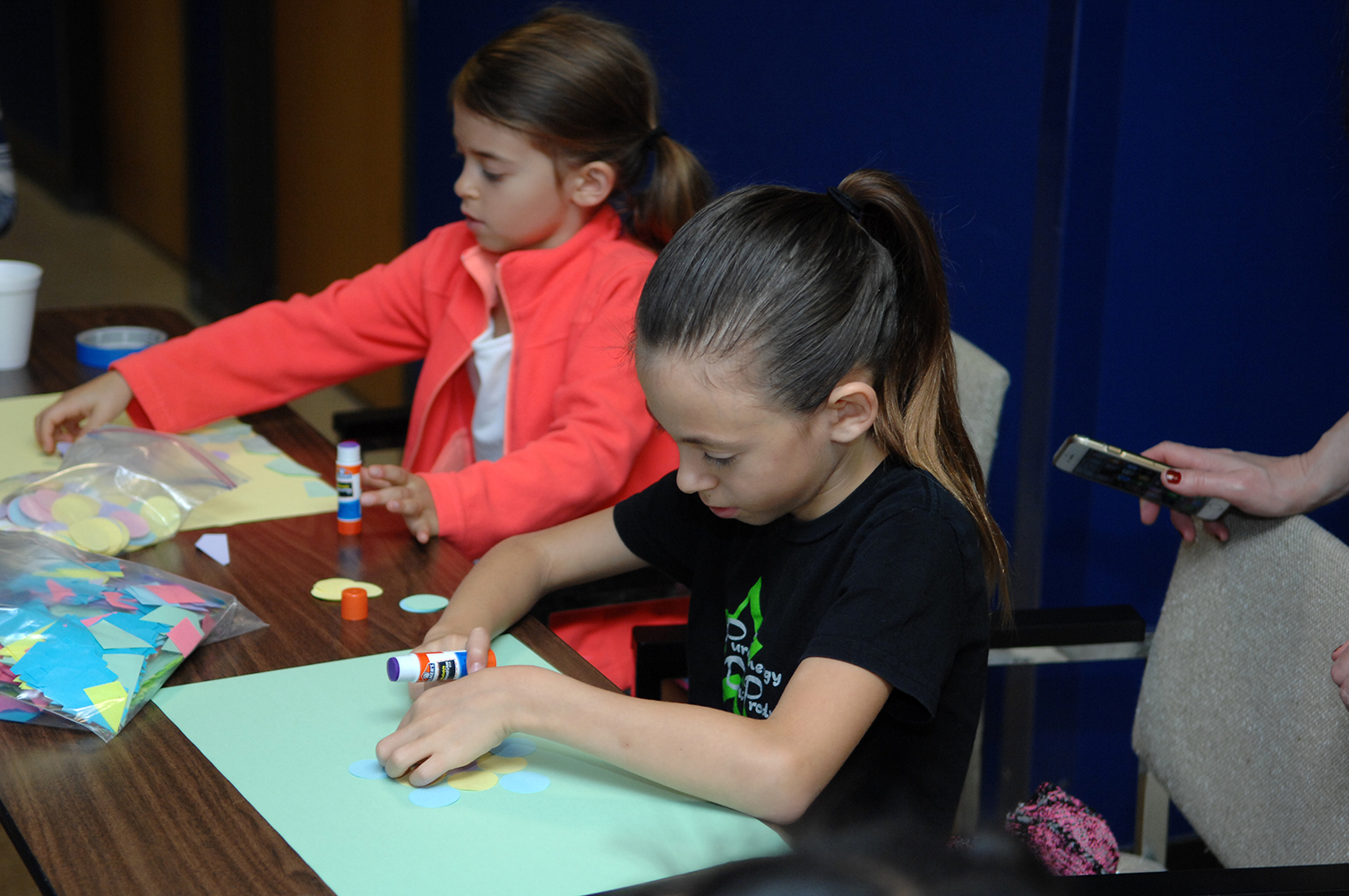 Two young female children complete a construction paper activity at the Texas A&M Mathematics and Statistics Fair