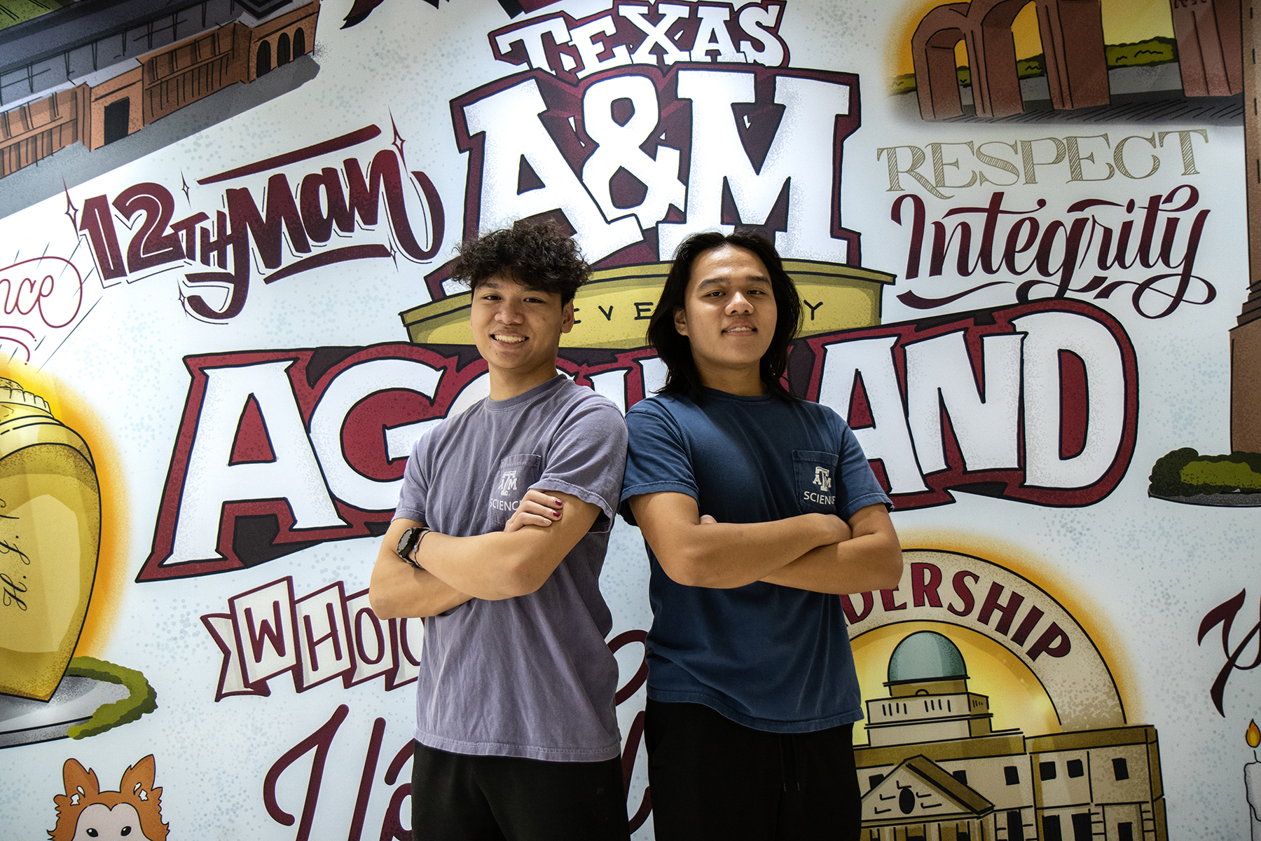 Texas A&amp;M biology majors and brothers Kyle and Henry Nguyen pose with arms crossed in front of a Texas A&amp;M-themed mural located in Rudder Tower on the Texas A&amp;M University campus