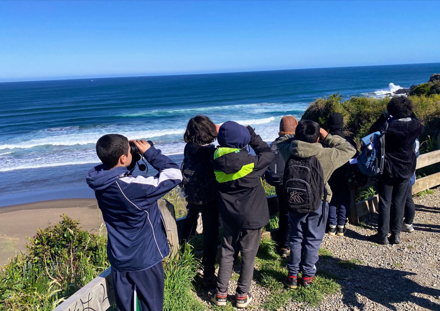 Los Pellines Intercultural Rural School students use binoculars to scan the shoreline for migratory birds and other scientific finds during a field trip to Calfuco Beach in Chile