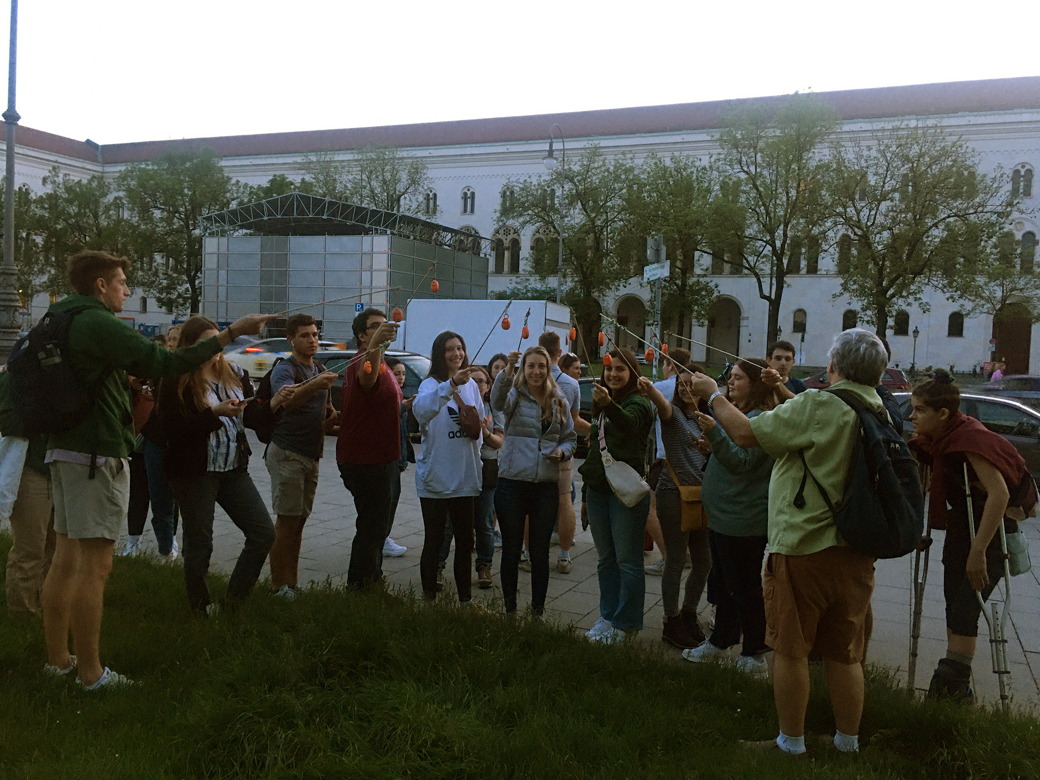 A group of Texas A&amp;M University meteorology students in Munich, Germany, stand close together on a city street while using temperature and humidity loggers mounted on small poles to measure air temperatures and other atmospheric conditions for a research project on urban heat islands