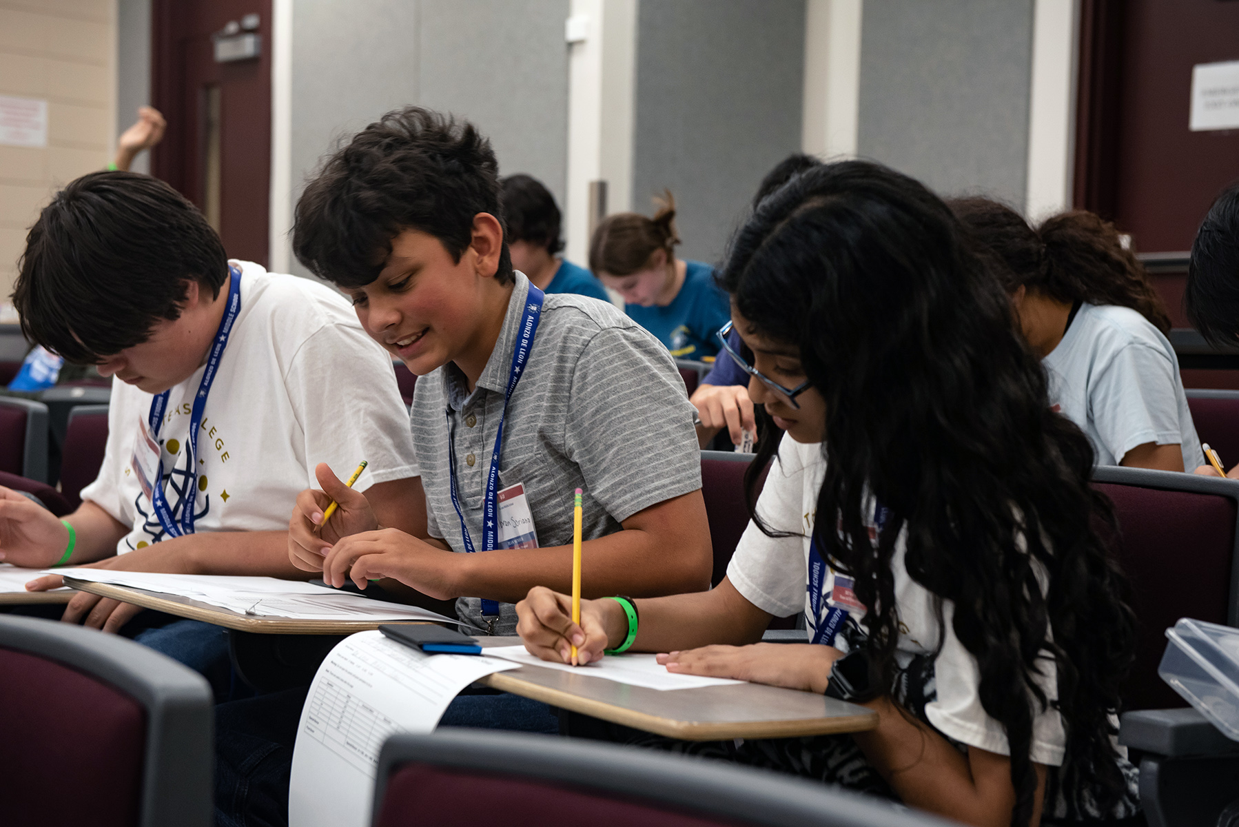 Students competing in the Texas Science Olympiad sit at desks in a classroom while solving problems to complete a written examination