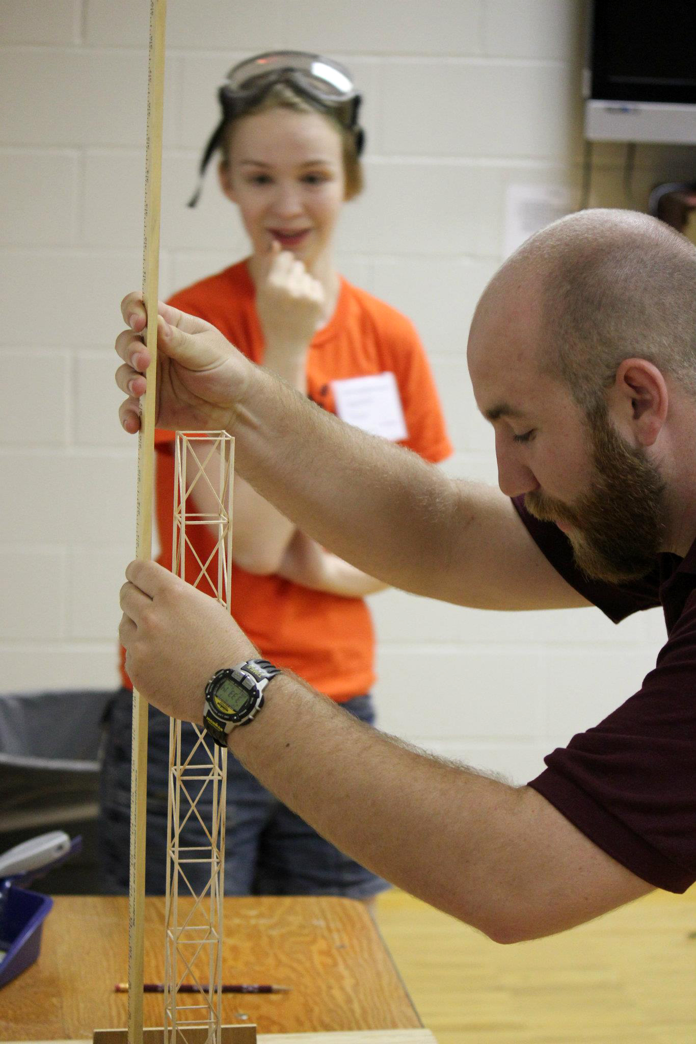 A young competitor eagerly watches as a judge measures her balsa wood tower during the "Towers" event at the Texas Science Olympiad