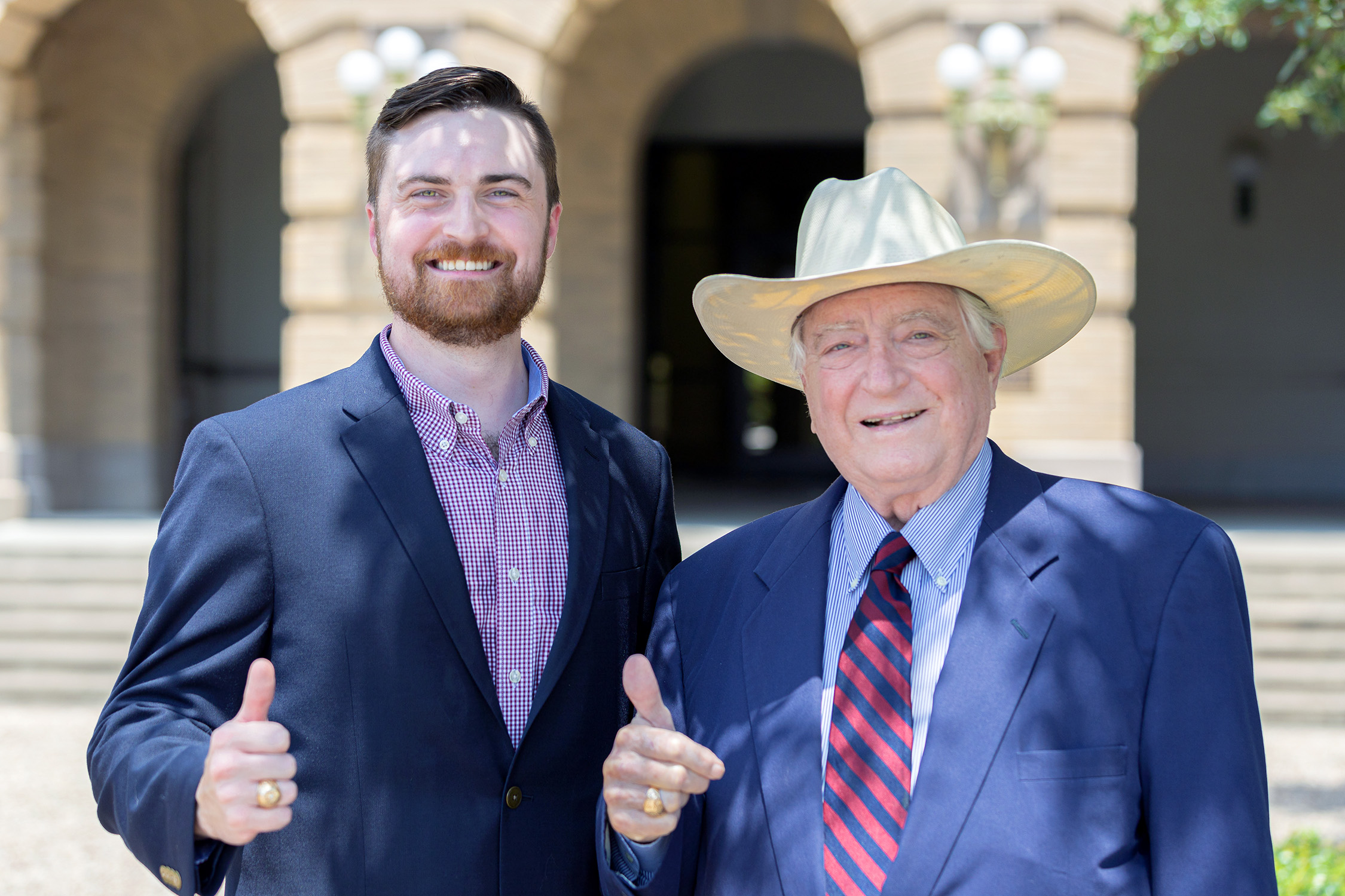 Luther Soules IV (left) and his father, Luke Soules flash an Aggie gig 'em/thumbs up for the camera outside the Academic Building on the Texas A&amp;M University campus