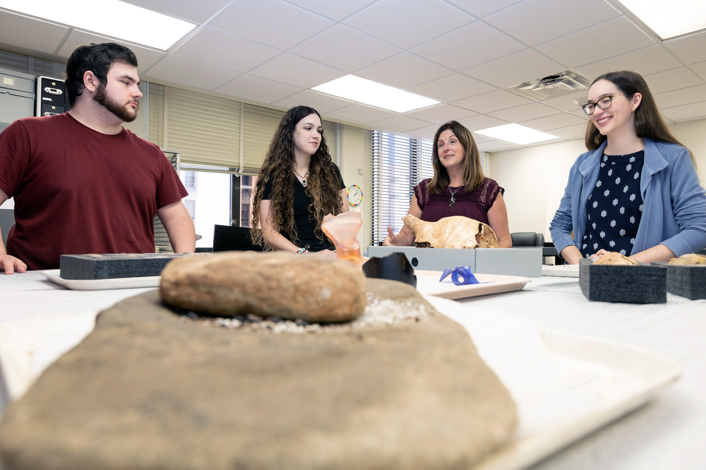 Dr. Katie Custer Bojakowski and other staff within Texas A&amp;M University's Anthropology Research Collections discuss an item within the collection at a table in the laboratory