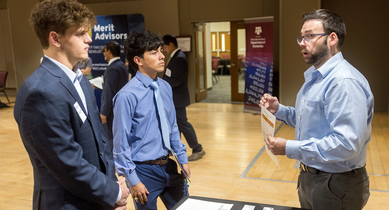 Two Texas A&M University economics majors speak with a recruiter at the 2024 Economics Career Fair, held September 25 in the Memorial Student Center on the Texas A&M campus