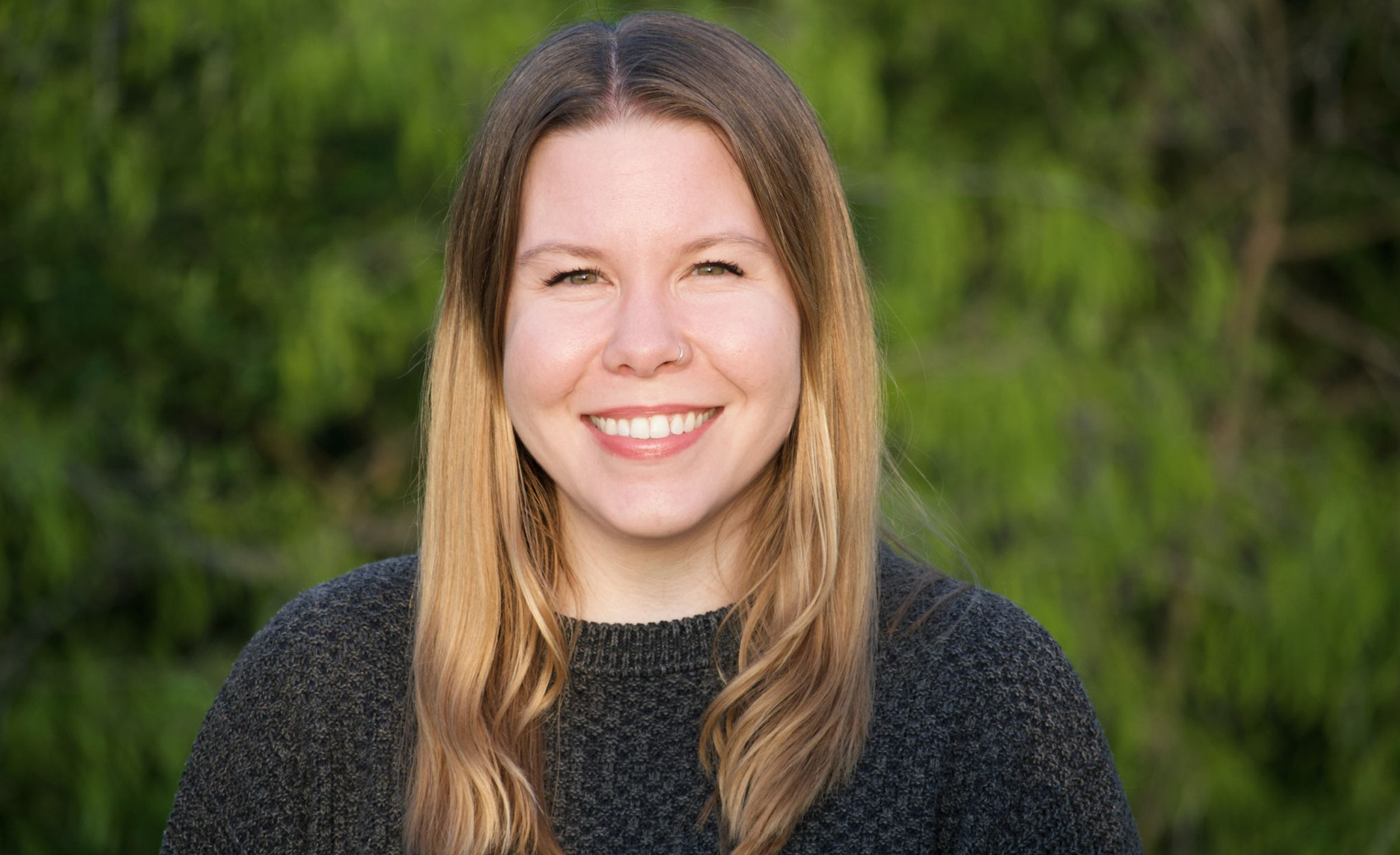 Alyssa Shultz smiling with a row of trees behind her